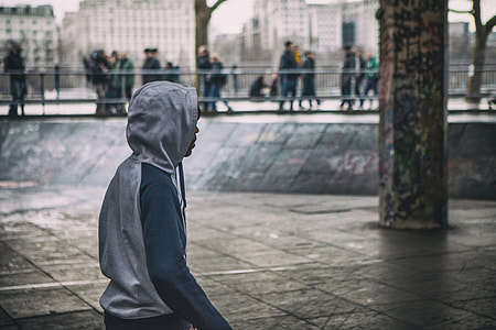A young man wearing a hooded top stands on the Southbank in London, England thumbnail