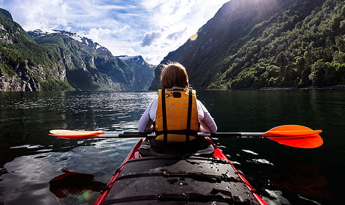 person riding paddle board holding oars during day time thumbnail