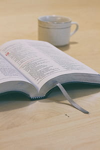 opened book beside white ceramic cup on top of beige surface thumbnail