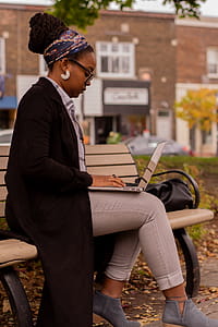Woman Sitting on Brown Wooden Bench Using Macbook Pro thumbnail