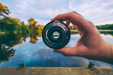 Closeup shot of a photographer man’s hand holding a camera lens thumbnail