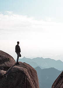 man standing on rock with view of mountain thumbnail