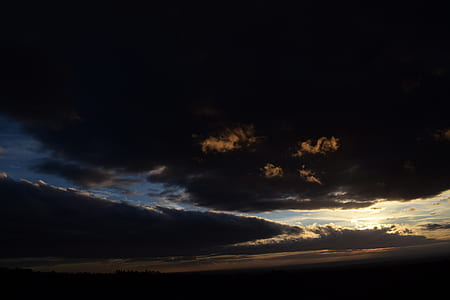 open field under blue, black, and yellow cloudy skies thumbnail