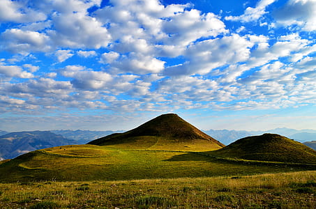 green hill under white clouds and blue sky during daytime thumbnail