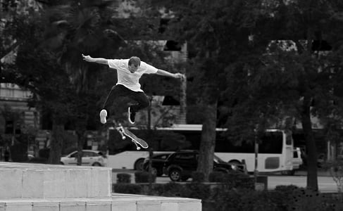 grayscale photography of man skateboarding while doing stunt on air thumbnail
