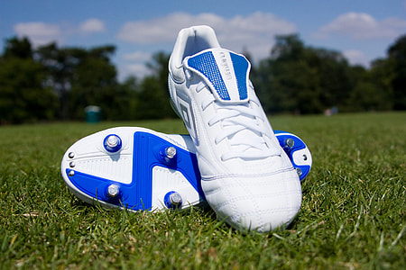 closeup photo of blue-and-white Umbro soccer cleats on green field during daytime thumbnail