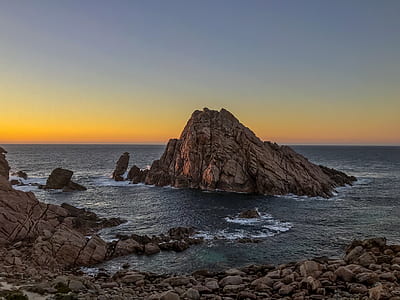 body of water hitting brown rock formation thumbnail