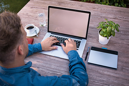 man using laptop computer beside coffee and potted plant thumbnail