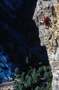 man wall climbing near green trees during daytime thumbnail