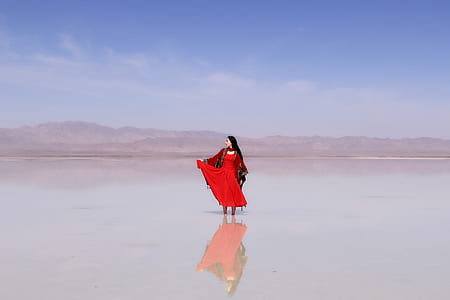woman in red sari dress on body of water during daytime thumbnail