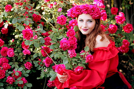 woman wearing red off-shoulder long-sleeved dress while holding red roses during daytime thumbnail