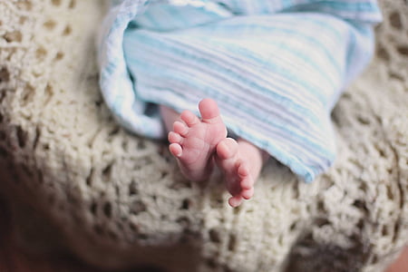 shallow focus photography of infant covered with white and teal blanket thumbnail