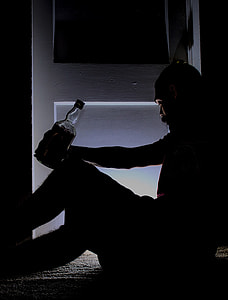 man sitting next to door holding bottle of liquor thumbnail