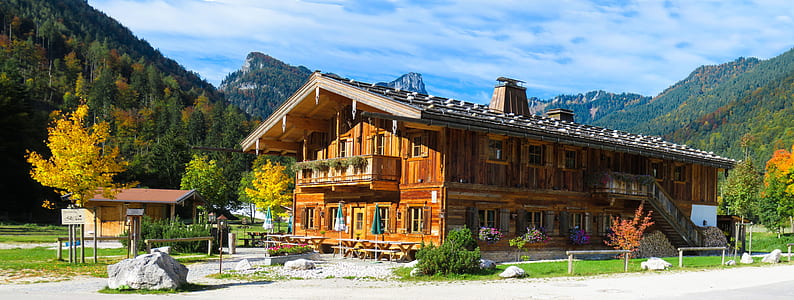 brown wooden house near mountain during daytime thumbnail