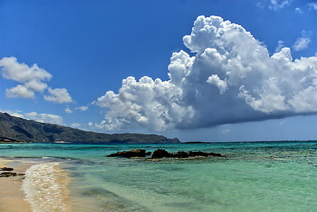 seashore under white clouds and blue sky during daytime thumbnail