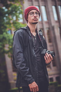 man holding DSLR camera near tree thumbnail