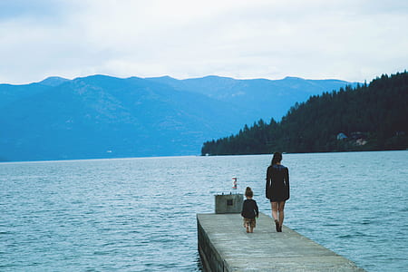 woman and child walking on the dock during daytime thumbnail