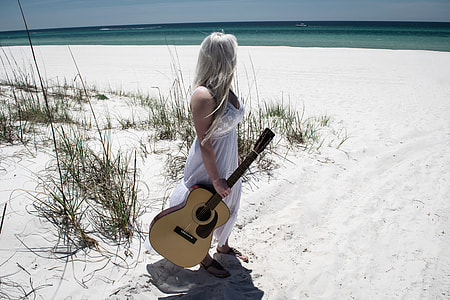 woman wearing white dress holding beige acoustic guitar on sea shore thumbnail