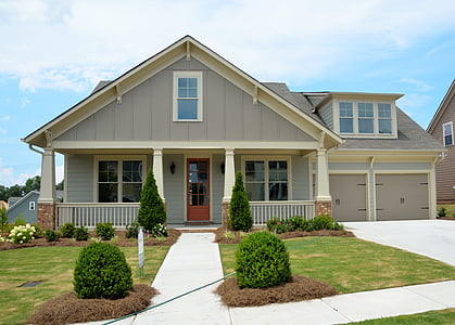 gray and white wooden house in front of bushes and lawn during daytime thumbnail