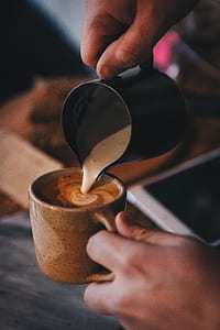 person holding up and pouring cream on coffee thumbnail