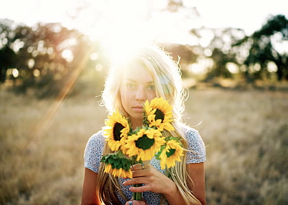 woman holding sunflowers during daytime thumbnail