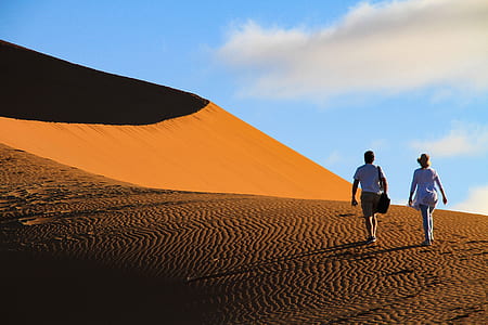two person walking on desert during daytime thumbnail