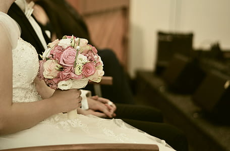 selective focus photography of woman in wedding dress holding bouquet of flowers thumbnail