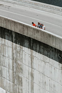 Four Persons Standing Beside Concrete Wall thumbnail
