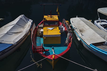 three assorted-color boats on body of water thumbnail