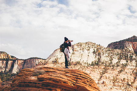 person taking photo while standing on brown stone at daytime thumbnail
