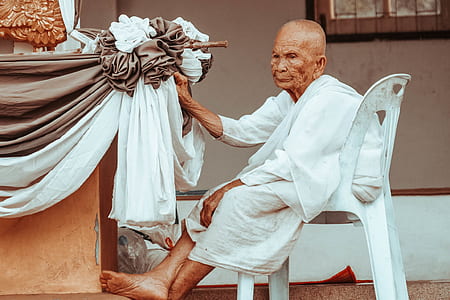 man sitting in white plastic chair thumbnail