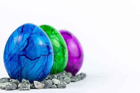 three blue, green, and purple eggs piled next to each other thumbnail