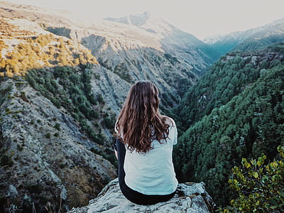 woman in white shirt sitting on top of gray rock thumbnail