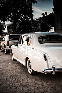 classic white hardtop sedan parked next to gray Chevrolet Tahoe SUV during daytime thumbnail