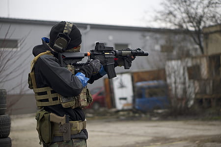man holding rifle selective focus photography thumbnail