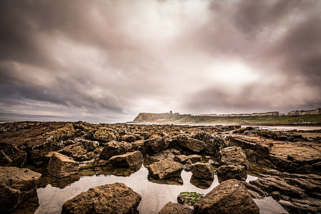 wide angle photo of brown rocks under cloudy sky thumbnail