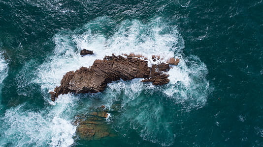 brown rock formation on surrounded by body of water thumbnail