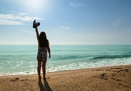 woman raising hand in front of ocean thumbnail