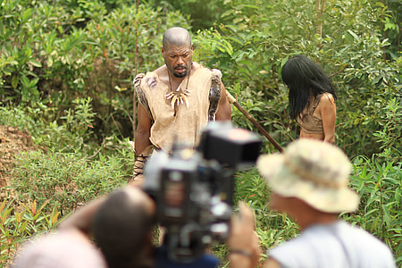 people filming man and woman standing near plants outdoors thumbnail