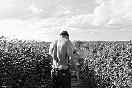grayscale photography of man in the middle of the grass field thumbnail