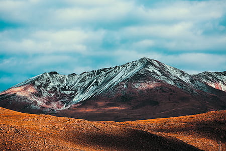 brown rocky mountain under blue cloudy sky during daytime photo thumbnail