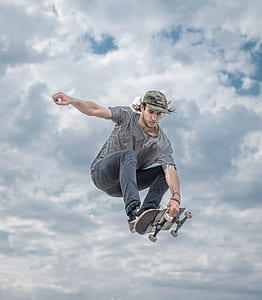 man doing tricks on skateboard under cloudy skies thumbnail