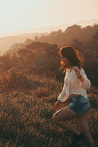 Women Wearing White Long-sleeved Blouse With Blue Denim Short Shorts Taken during Sunset thumbnail