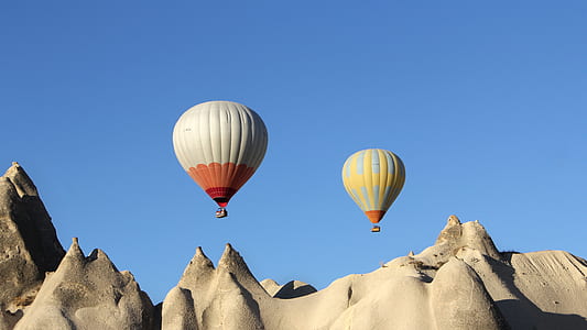 two white and gray air balloons under hills at dayatime thumbnail