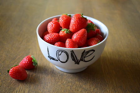 round white bowl with Love text of red Strawberries on brown wooden table thumbnail