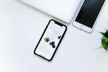 space gray iPhone X displaying silver MacBook beside DSLR camera thumbnail