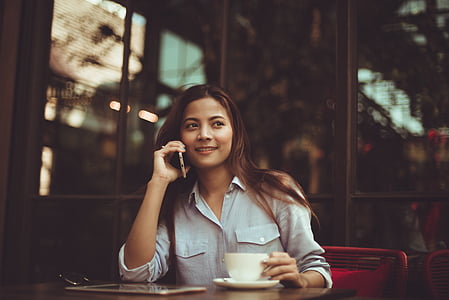 selective focus photography of woman in blue button-up shirt sitting in front of brown table thumbnail