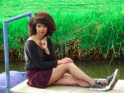 woman sitting on platform while facing the camera during daytime thumbnail