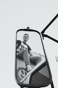reflection of man from a mirror sitting on compartment of truck thumbnail