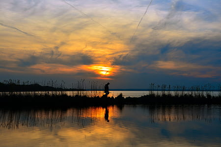 silhouette photo of person standing near body of water thumbnail